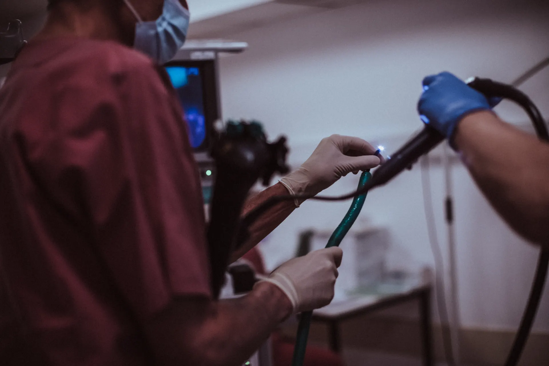 Hands of the endoscopy team at the gastroscope, with the monitor in the background
