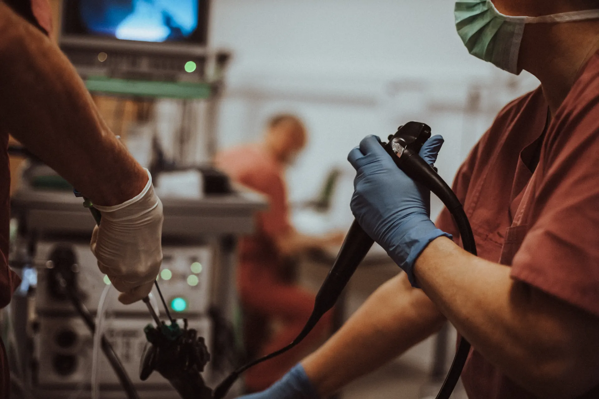 Doctor guiding an endoscope in the treatment room, with the monitor in the background