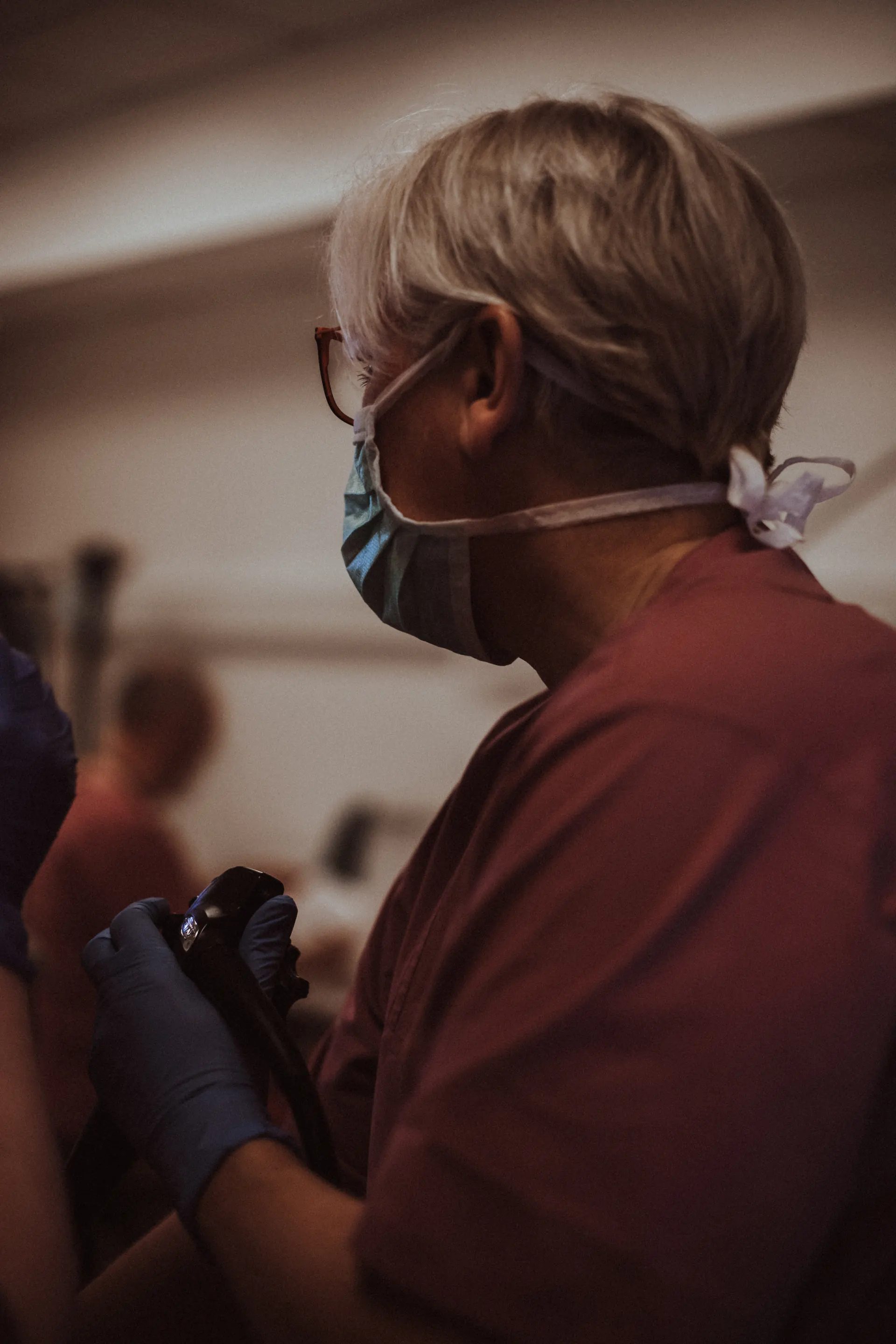 Team member wearing a mask and glasses holding an endoscope in the endoscopy room